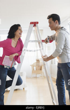 Couple talking at ladder during home remodeling Stock Photo