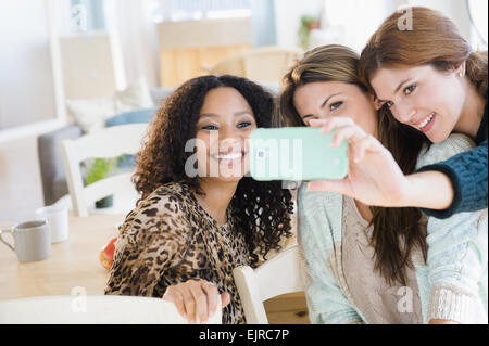 Women taking cell phone photograph in dining room Stock Photo