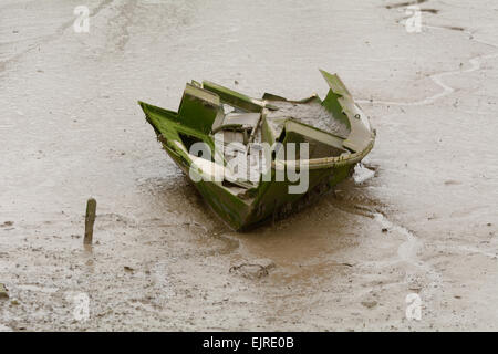 Damaged small rowing boat in mud on the River Taw, Fremington, Devon, England