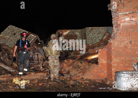 An Oklahoma National Guard soldier and firefighter search for survivors through the rubble of a building that was devastated by a tornado in Moore, Okla., May 20, 2013. The guardsman is assigned to the 700th Brigade Support Battalion, 45th Infantry Brigade Combat Team.  Sgt. 1st Class Kendall James Stock Photo