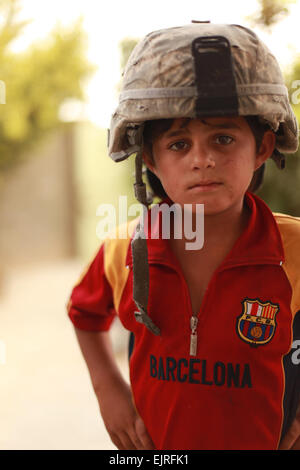 A local child wears a U.S. Army kevlar helmet as Iraqi police and U.S. Soldiers with the 1st Battalion, 8th Cavalry, 2nd Brigade Combat Team, 1st Cavalry Division, interview candidates for micro-grants in Altun Kupri, Iraq, Sept. 7, 2009.   /  /  . Stock Photo