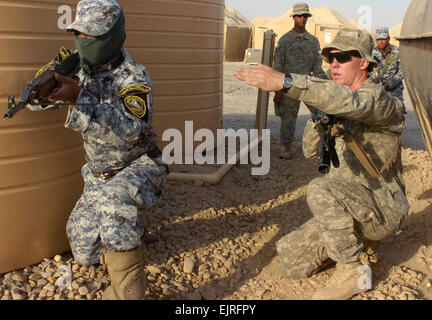 Pvt. Nicholas Culpepper, of Raleigh, N.C., advises a National Police officer assigned to the 3rd NP Brigade, 1st NP Division to point his weapon toward a certain direction in order to provide security for his fellow officers who are entering and clearing a home during a training event, June 24, at Forward Operating Base Hammer, Iraq, located outside of eastern Baghdad. Culpepper and Paratroopers assigned to Troop K, 5th Squadron, 73rd Cavalry, 82nd Airborne Division, are training and mentoring their Iraqi partners as part of a two-week course in the unit's newly developed training academy. Pho Stock Photo