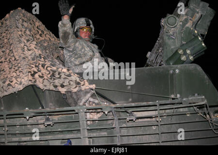 A soldier with the 4th Stryker Brigade Combat Team, 2nd Infantry Division waves as he and his fellow Strykers roll across the boarder from Iraq into Kuwait in the early morning hours of Aug. 19. The 4/2 convoyed their own vehicles out of Iraq after a year-long tour there, bringing troop levels in the country closer to the 50,000 mark. The 1st Theater Sustainment Command played an important role in the withdrawl of the 4/2 by providing facilities needed for the soldiers to clean and ship their equipment to the United States. Stock Photo