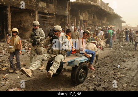 A U.S. Soldier from 1st Brigade Combat Team, 6th Infantry Division, assigned to Task Force Regulars receives a lift from an Iraqi boy and his mule on Route Douglas in the Jameela Market in the Sadr City district of Baghdad, Iraq, May 31, 2008.  Tech. Sgt. Cohen A. Young Stock Photo