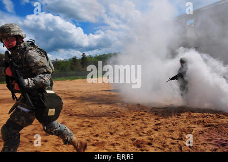 U.S. Army Lt. Col. Anthony Digiacomo emerges from a smoke cloud while providing simulated cover fire for Spc. Sean White during training on the military operations in urban terrain obstacle course on Camp Grayling, Mich., June 10, 2008. The Soldiers are participating in the National Guard Stock Photo