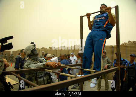 An Iraqi police applicant performs pull ups during the physical fitness test portion of the application process in Sheik Amir, Iraq, July 8, 2008, as Iraqi and coalition forces observe.  Spc. Daniel Herrera, Stock Photo
