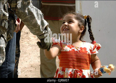 A young Iraqi girl shakes the hand of a U.S. Army soldier at the Neighborhood Activities Center in the Gazaliyah district, Baghdad, Iraq, Sept. 21, 2008. The soldier is assigned to the Green Platoon, Bravo Troop, 1st Squadron, 75th Cavalry, 2nd Brigade Combat Team, 101st Airborne Division.   Spc. Charles W. Gill Stock Photo