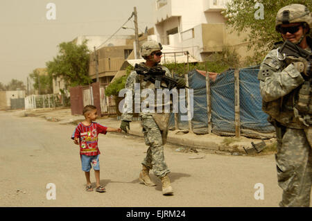 3rd Brigade Combat Team, 4th Infantry Division Personal Security Detail Sgt. Kevin Dodson of Colorado Springs, Colo., leads the way as Spc. Fout is escorted by a young Iraqi boy through Muhalla 511 in the Sadr City district of Baghdad on Sept. 27, 2008. Stock Photo