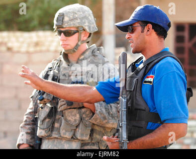An Iraqi police officer shows Cpl. Randall Robinson, from Charleston, S.C., the different features of a checkpoint while on a patrol in the town of Narhwan, Oct. 9, 2008. Stock Photo