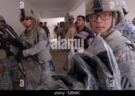 FORWARD OPERATING BASE FALCON, Iraq - Spc. Christopher McDonald, an infantryman assigned to Company A, 4th Battalion, 64th Armor Regiment, holds an armful of backpacks during a school supply distribution Oct. 14 at the Ishtar School in the Risalah community of southern Baghdad. McDonald, who hails from Hickory, N.C., is attached to the 1st Brigade Combat Team, 4th Infantry Division, Multi-National Division ñ Baghdad, serving a 15-month deployment in support of Operation Iraqi Freedom. Soldiers and National Policemen from the 5th Brigade, 2nd NP Division, distributed school supplies to approxim Stock Photo