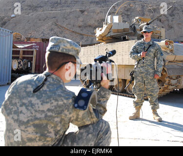 Spc. David Allen, from Allentown, Penn., who serves with Company B, 1st Battalion, 6th Infantry Regiment, Task Force 1-35, 2nd Brigade Combat Team, 1st Armored Division, Multi-National Division-Baghdad, gives a holiday shout-out while Staff Sgt. Kelly Collett, from Salt Lake City, Utah, 128th Mobile Public Affairs Detachment, Division Special Troops Battalion, MND-B, records the season's greetings from Combat Outpost Cashe, Iraq, Dec. 12. Stock Photo