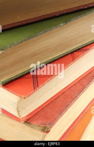 Many different colored books are stacked atop each other Stock Photo