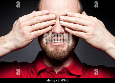 smiling man hide his eyes with hands Stock Photo