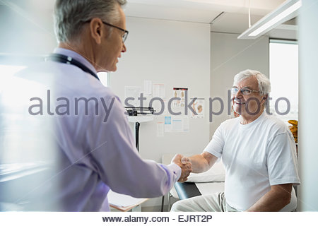 Doctor handshaking with senior man in examination room