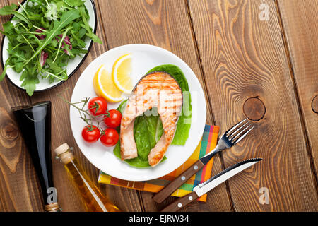 Grilled salmon, salad and condiments on wooden table. Top view with copy space Stock Photo