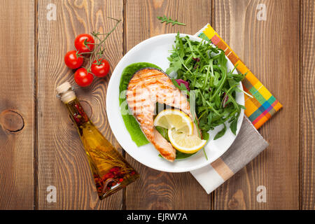 Grilled salmon, salad and condiments on wooden table. Top view Stock Photo