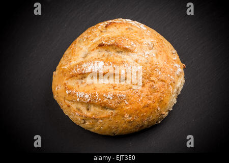 Whole Sesame Roll on Black Slate Board Isolated on a White Background Stock Photo