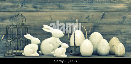 Easter bunnies and eggs on rustic wooden background. Vintage decoration with birdcage. Stock Photo