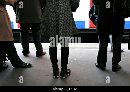 Commuters stand on a station platform Stock Photo