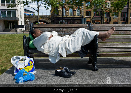 An Indian sleeps on a bench in London Stock Photo