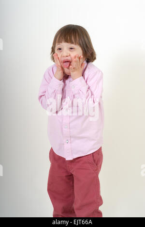 Boy with down syndrome with his tongue sticking out,  isolated on white background. Stock Photo