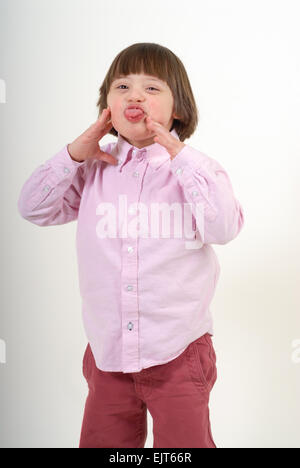 Boy with down syndrome sticking his tongue out,  isolated on white background. Stock Photo