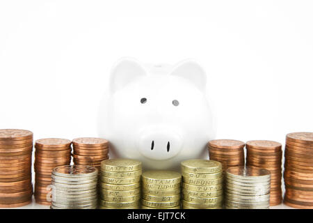 White Piggy bank With British Coins stacked in front, Stock Photo