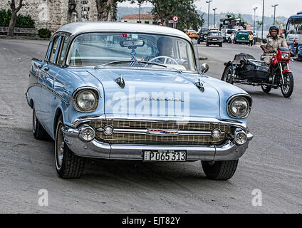 Old light blue Chevrolet American car in Havana Cuba with an old motor cycle Stock Photo