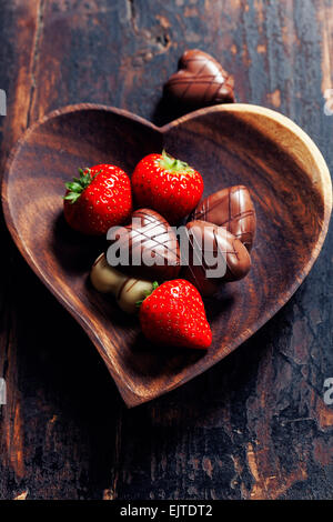 heart shape plate with strawberries and chocolate on wooden table - Valentine's day and love concept Stock Photo