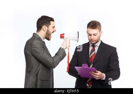 Businessman yelling through a megaphone at a colleague who has a clipboard in hand Stock Photo