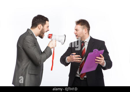 Businessman yelling through a megaphone at a colleague who has a clipboard in hand arguing with him Stock Photo