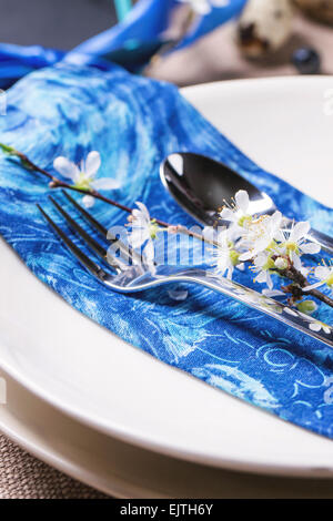 Easter table setting with blue textile napkin and blossom cherry branch Stock Photo