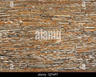 Background of old rusty drill bits of various sizes lying on a white table. Stock Photo