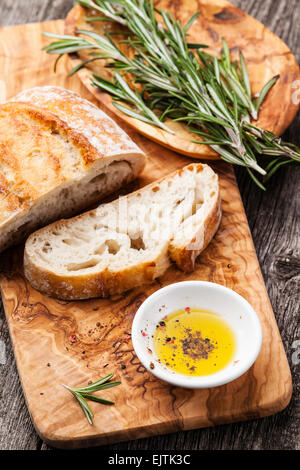 Sliced bread Ciabatta and extra virgin Olive oil on olive wood cookware background Stock Photo