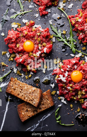 Beef tartare with fresh toasts on dark marble background Stock Photo