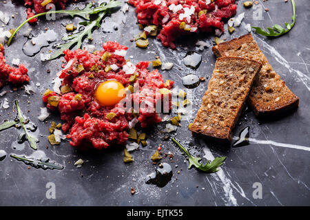 Beef tartare with fresh toasts on dark marble background Stock Photo