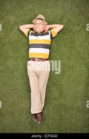 Relaxed senior gentleman lying on grass in a field and looking up in the sky Stock Photo