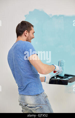 happy man with roller painting wall at home Stock Photo
