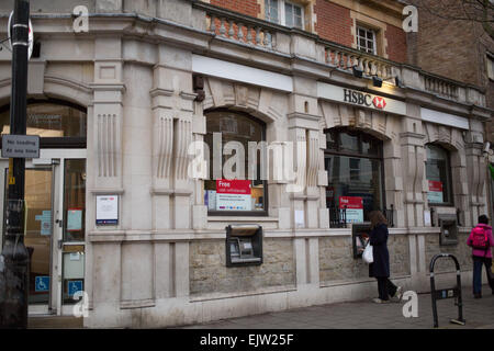 Woman using an ATM machine at an HSBC branch on Lordship Lane, East Dulwich London Stock Photo