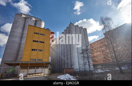Factory exterior with big concrete grain silos and manufacturing building in Finland on a sunny spring day. This majestic old in Stock Photo