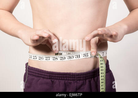 White Teenage boy measuring his stomach. Studio shot Stock Photo
