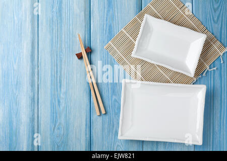 Empty plates and chopsticks on blue wooden background. Top view with copy space Stock Photo