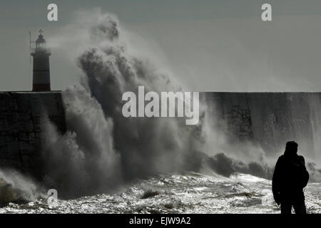 A man watches as waves crash against the harbour wall at Newhaven in East Sussex, UK Stock Photo