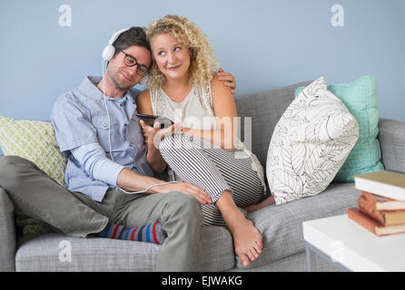 Couple sitting on sofa listening to music Stock Photo