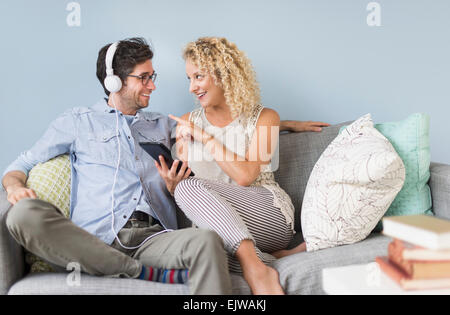 Couple sitting on sofa listening to music Stock Photo