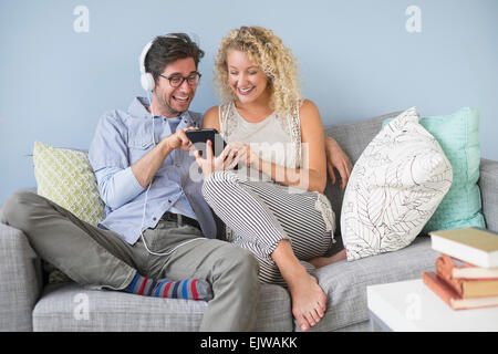 Couple sitting on sofa listening to music Stock Photo