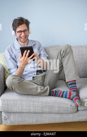 Man sitting on sofa listening to music Stock Photo