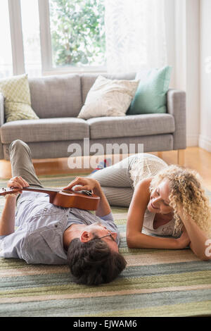 Couple lying on floor playing ukulele Stock Photo