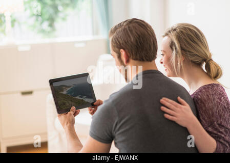 Rear view of couple looking at picture on digital tablet Stock Photo