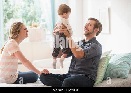 Happy parents playing with little son (2-3 years) on bed Stock Photo